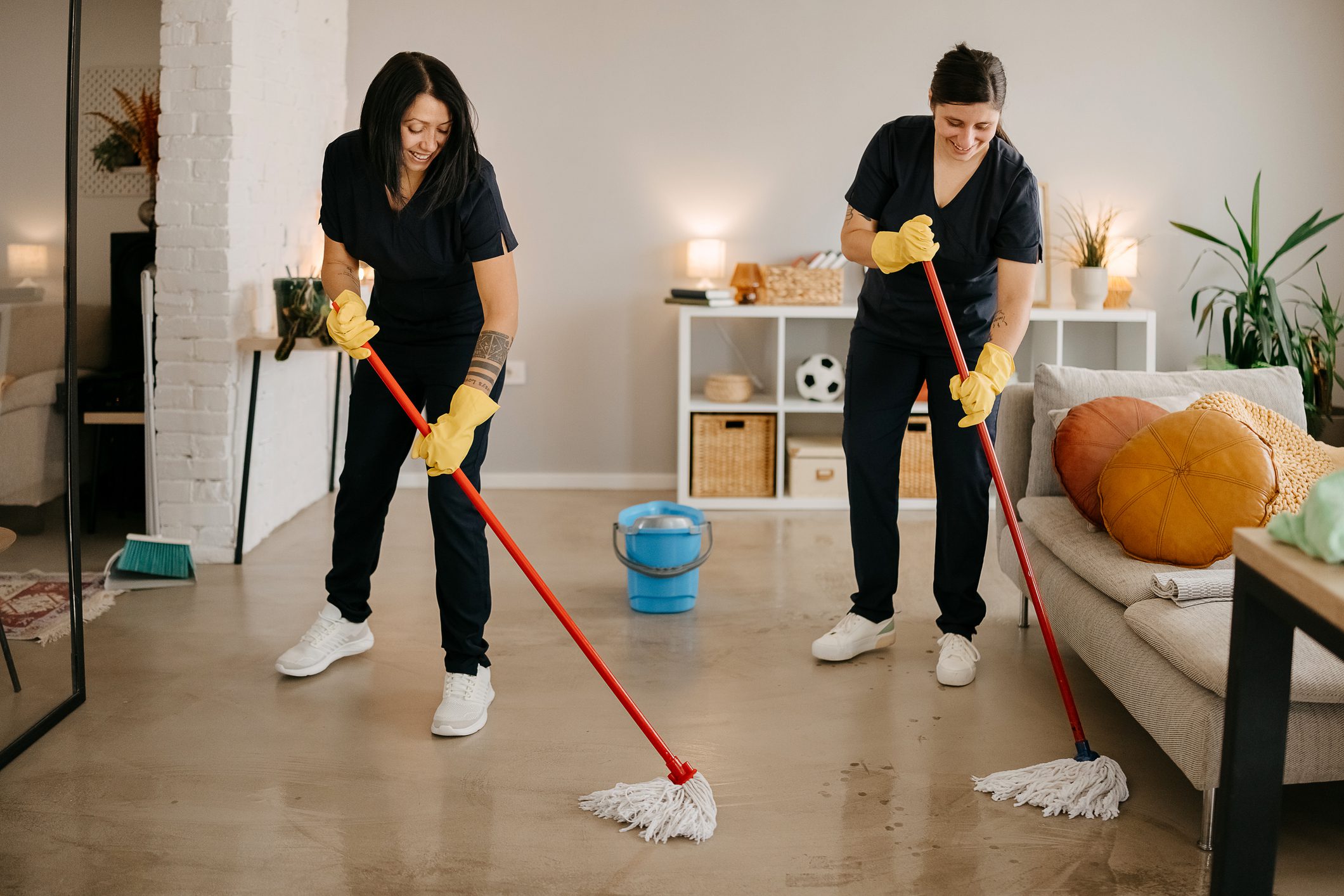 Two people mopping a living room floor