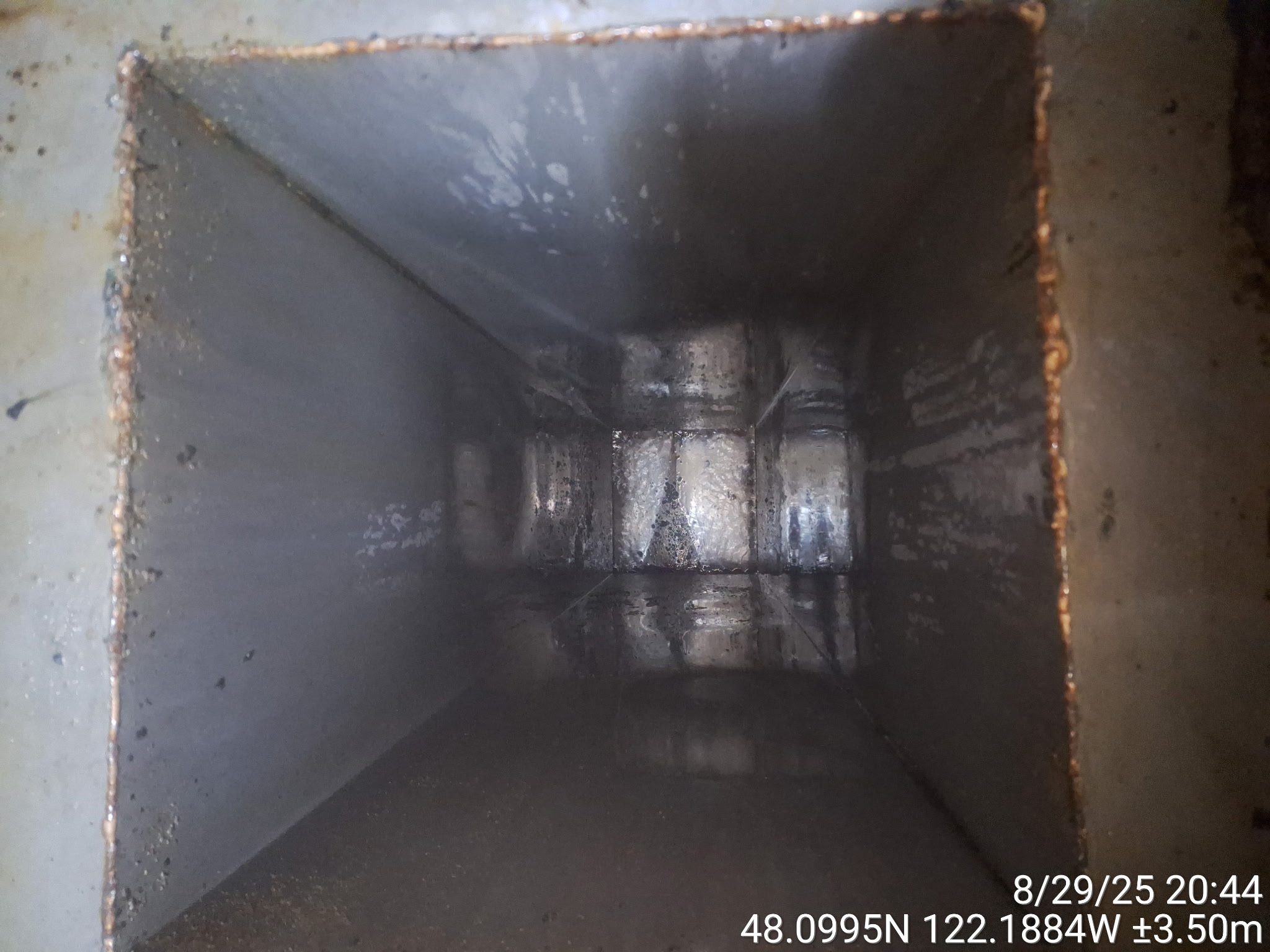 Inside view of a large metallic industrial duct or ventilation shaft.