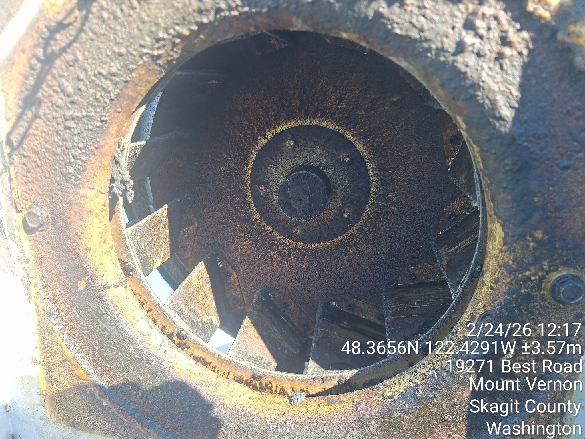 Close-up of a rusty turbine or fan blade inside a circular metal casing.