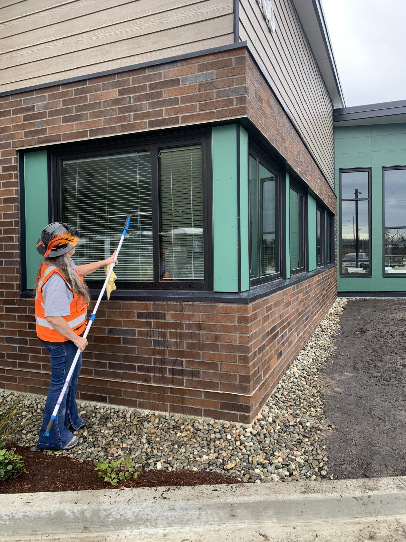 Worker cleaning windows on a brick building corner.