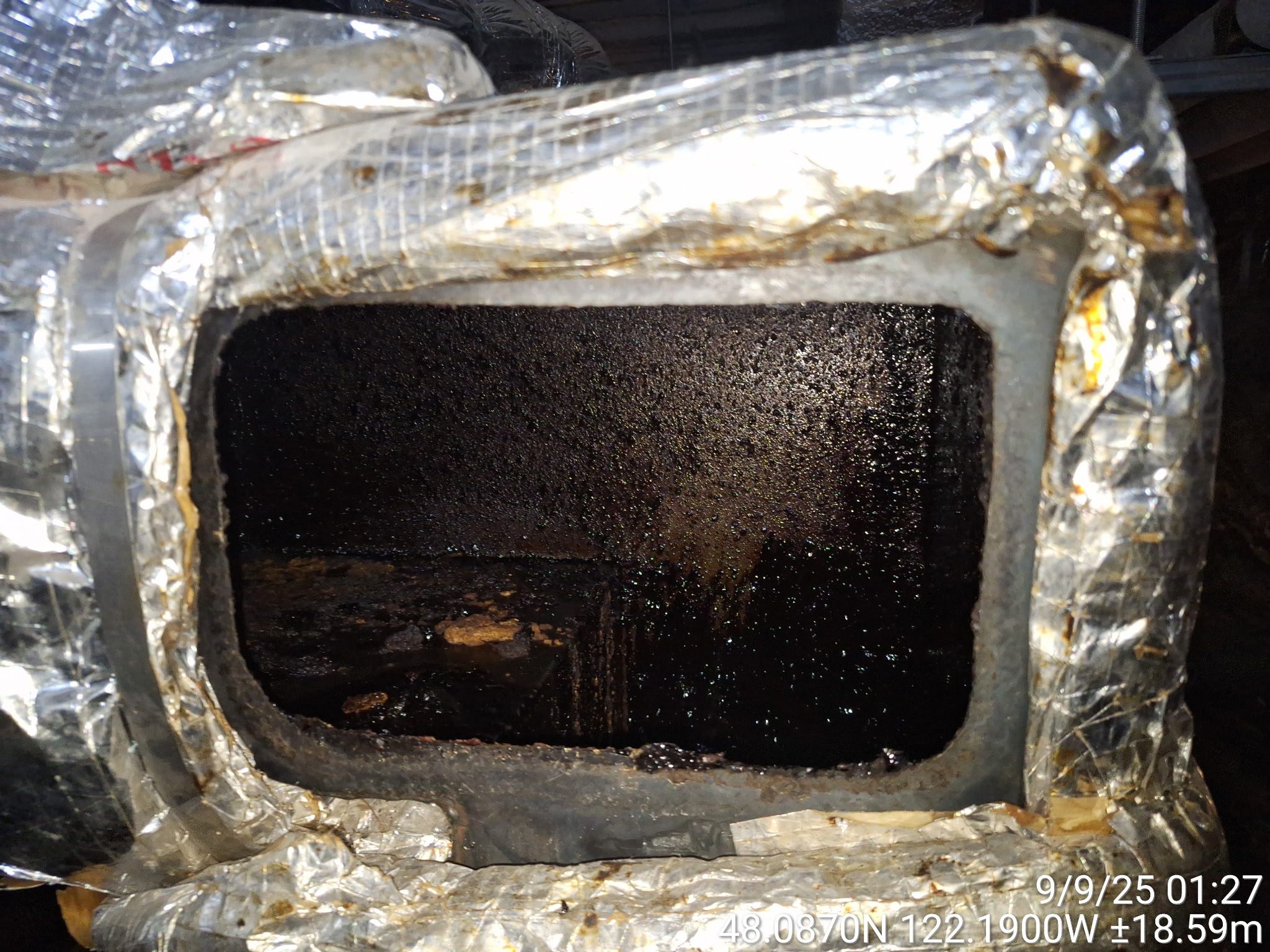A dark, greasy engine component with a rectangular opening.