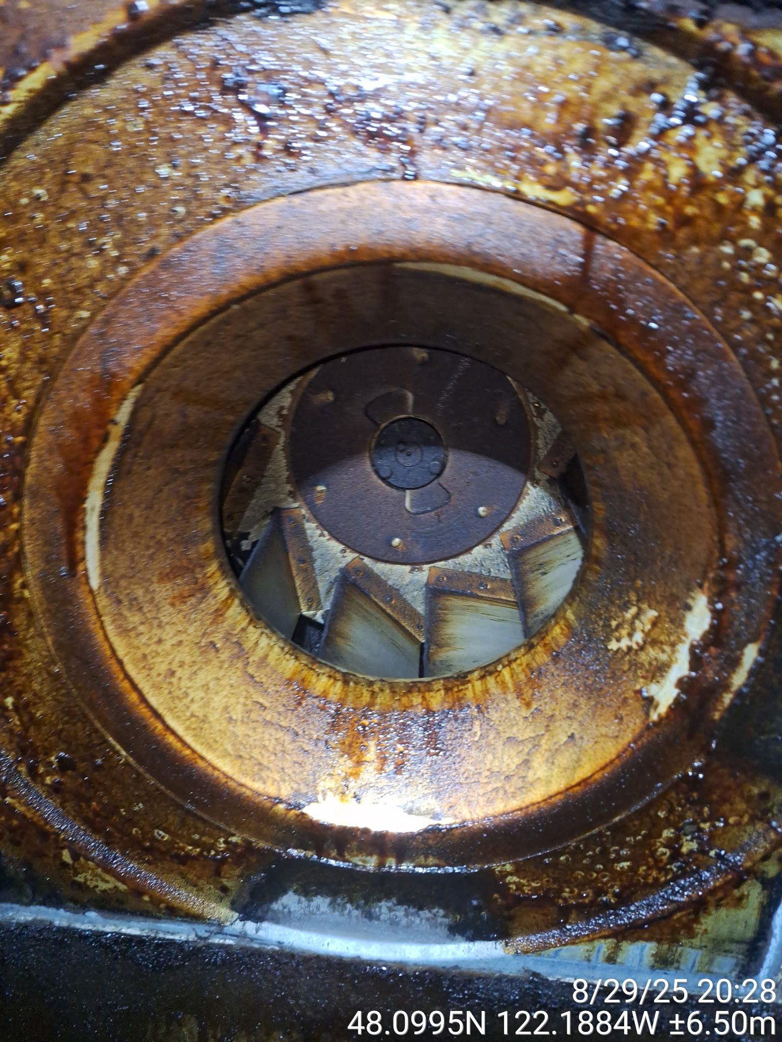Close-up of a rusty, corroded industrial fan blade inside a metal casing.