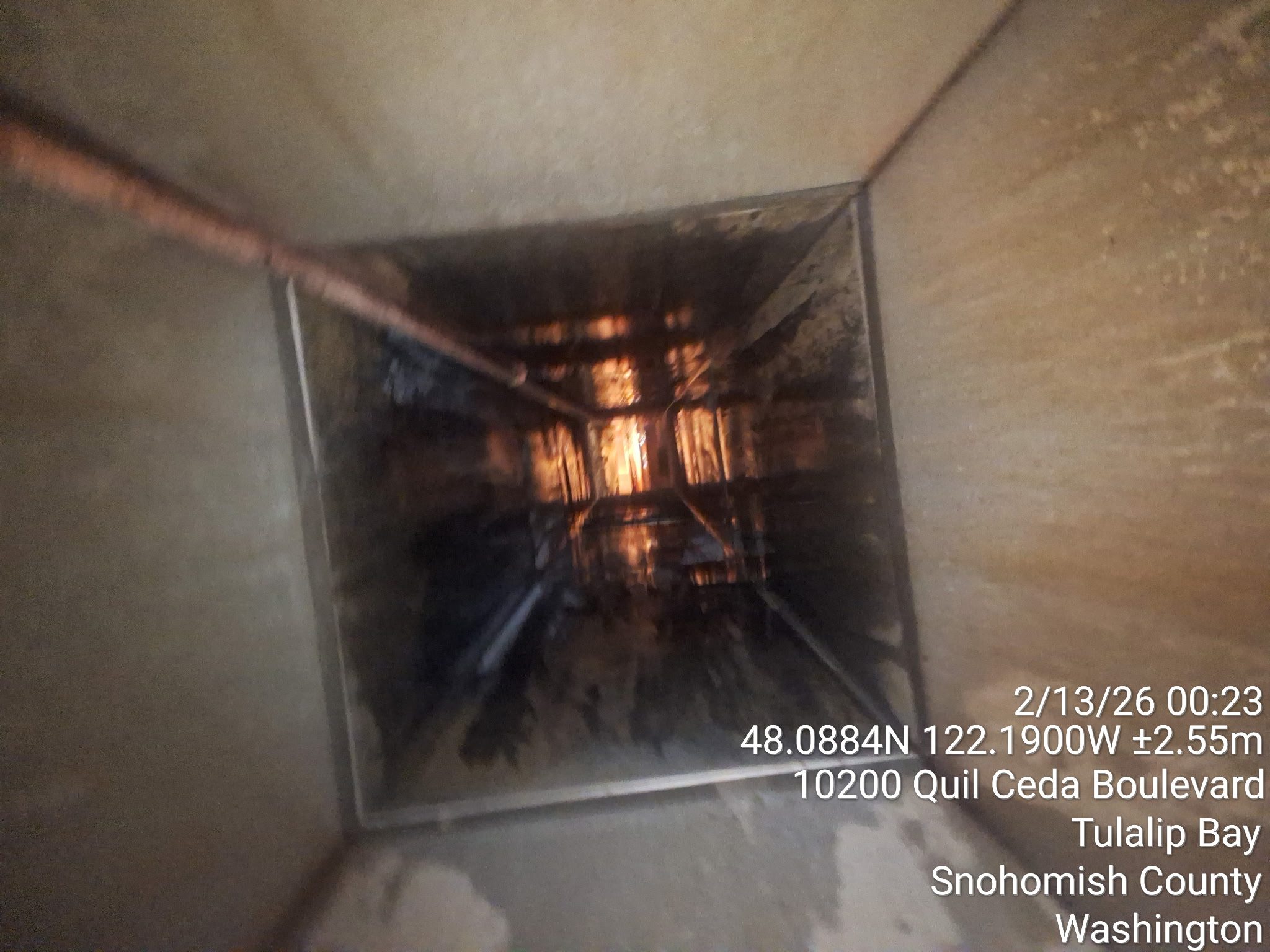 View looking down a tall elevator shaft with visible cables and machinery.
