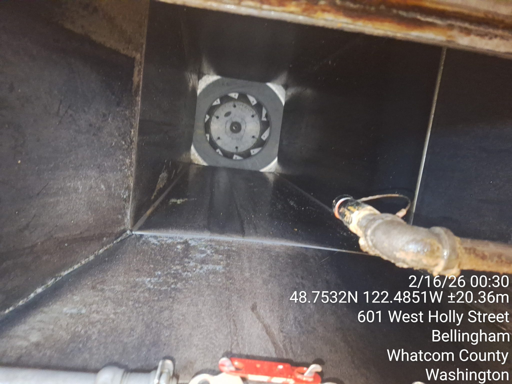 Inside view of a large metallic ventilation duct with a circular fan at the end.