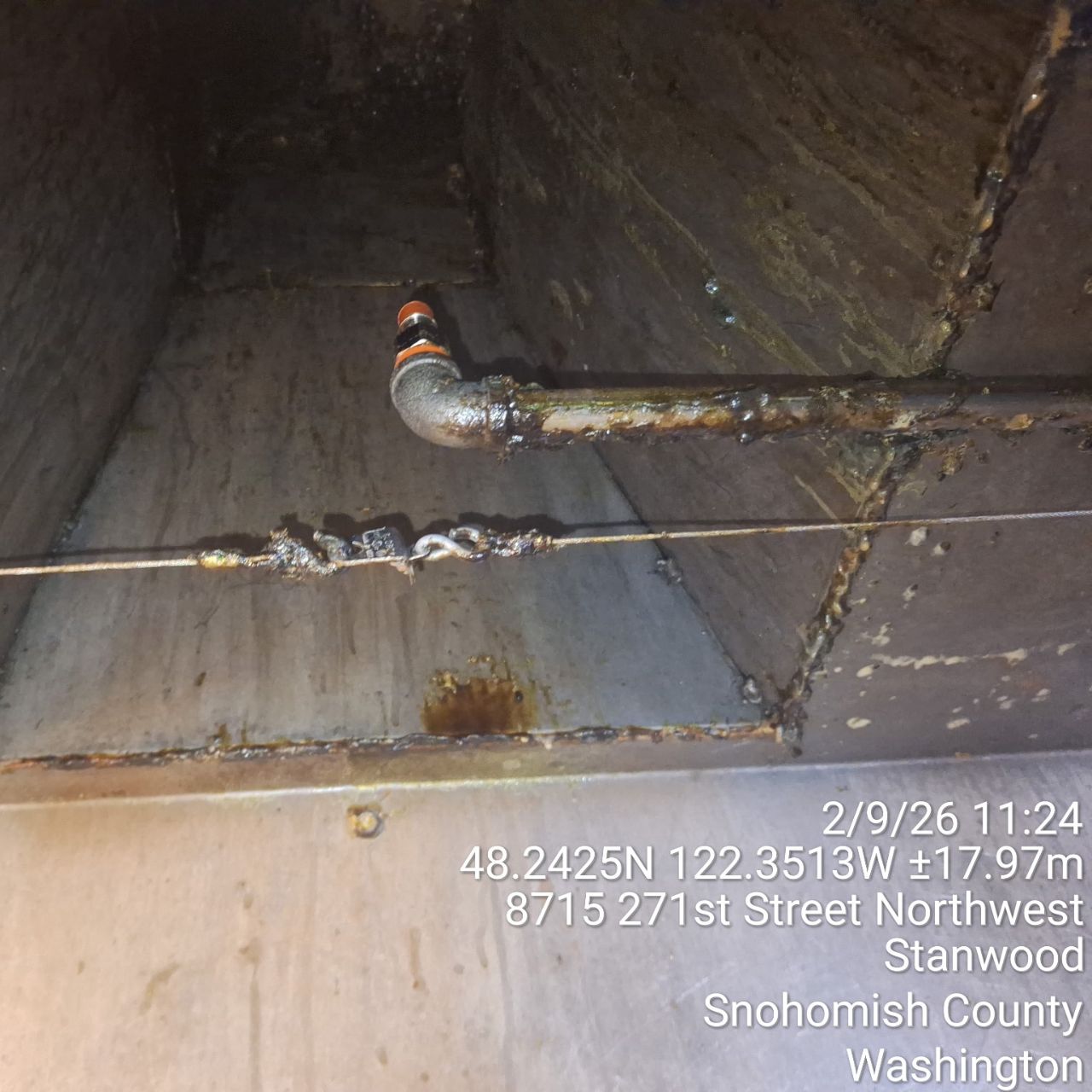 Corroded pipe with visible rust and water damage inside a concrete structure.