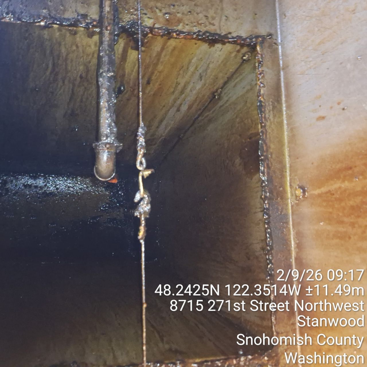Rusted metal structure with a hanging rope inside an industrial setting.