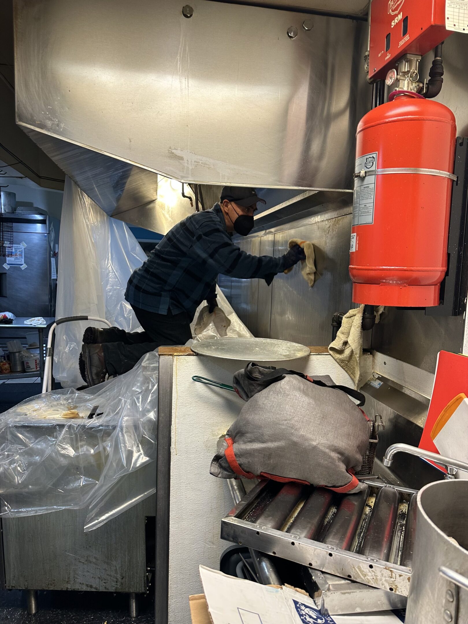 Person cleaning a kitchen vent hood in a commercial kitchen.