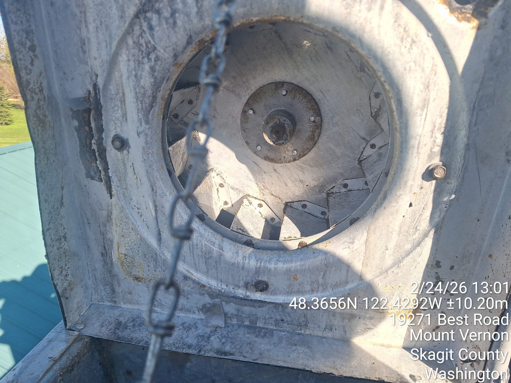 Close-up of a large industrial fan with protective mesh and shadows.