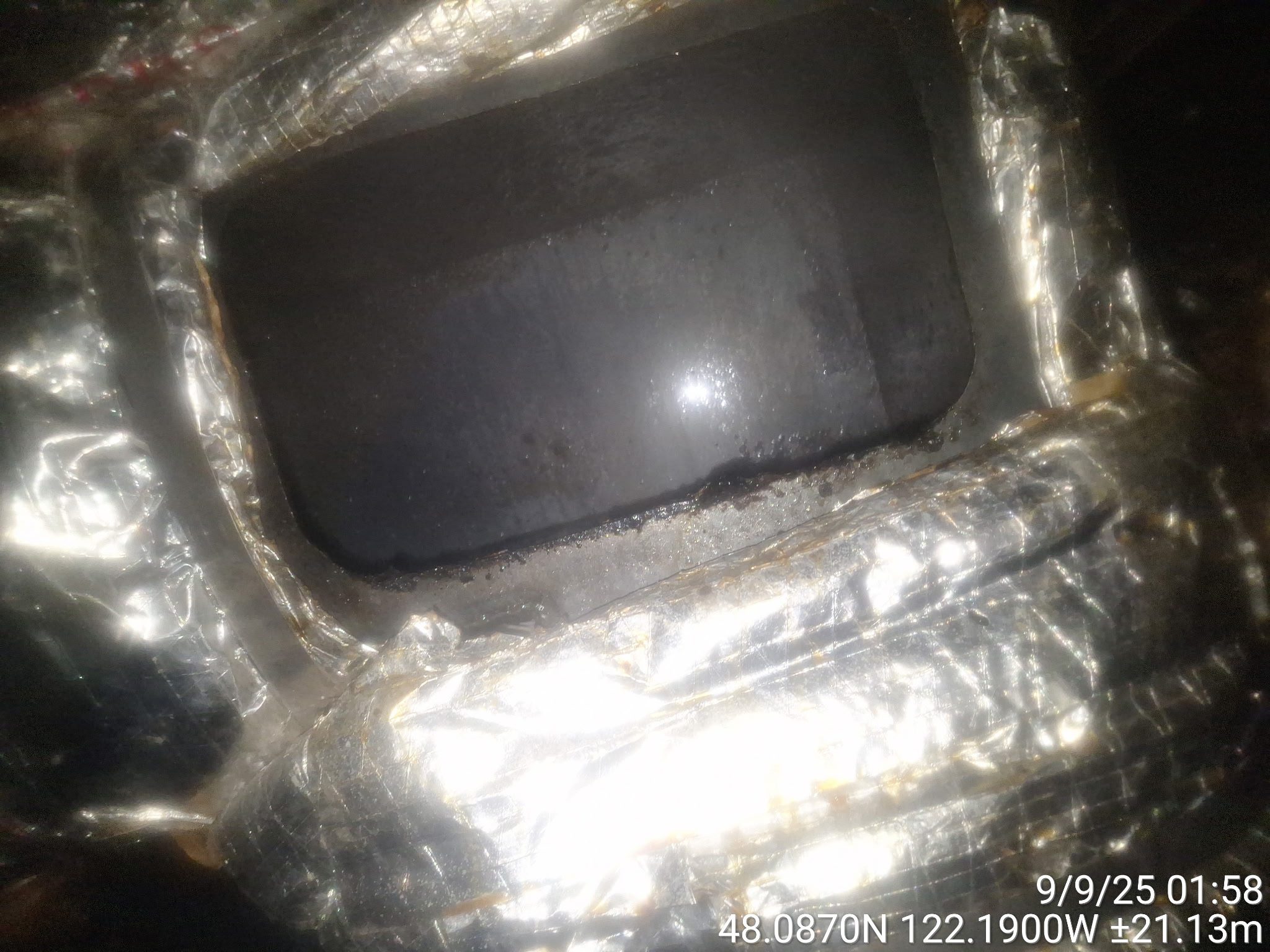 Close-up of a metallic object with a dark rectangular screen or window.