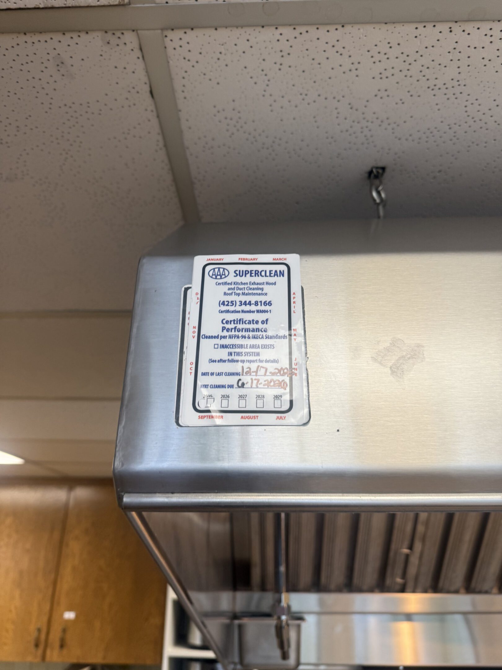 Metal kitchen hood with a safety instruction sign in a commercial kitchen.
