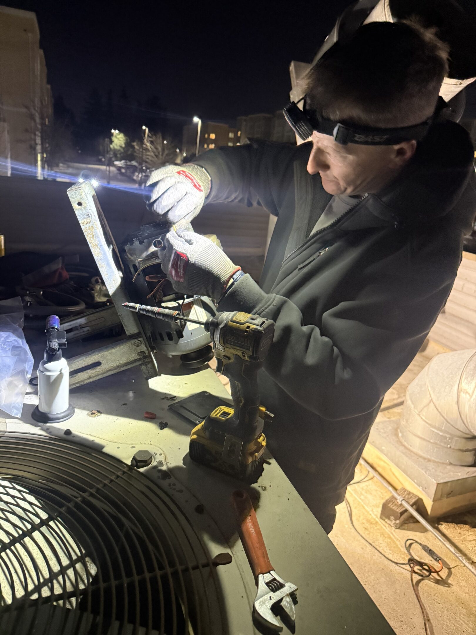 Person working with tools under dim lighting, wearing safety glasses.