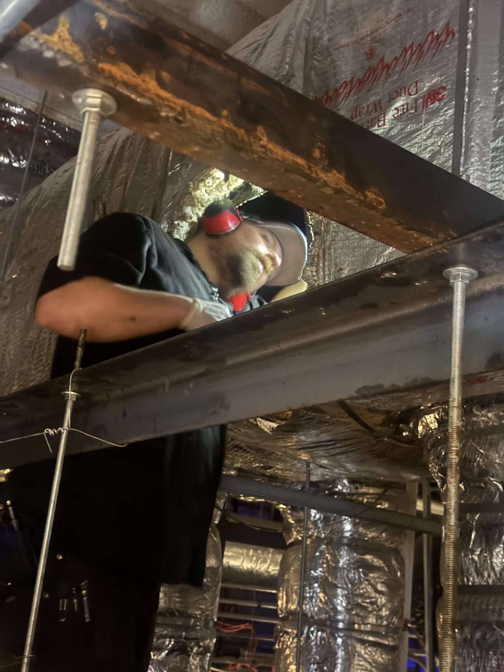Worker welding metal beams in a construction setting.