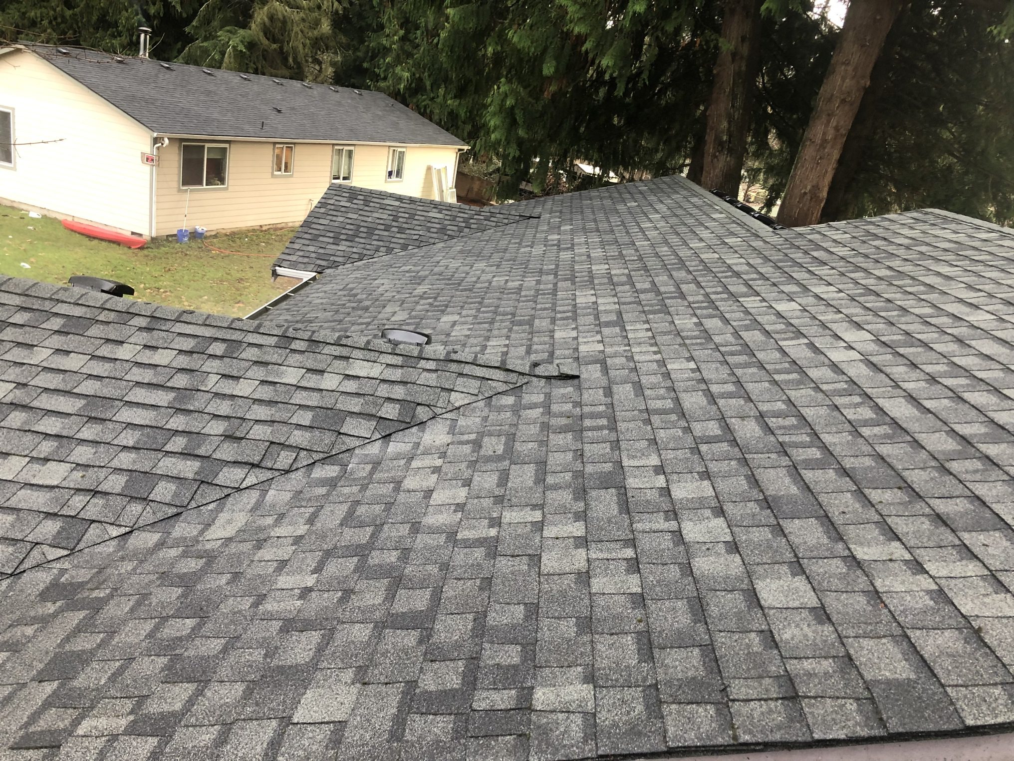 Close-up of a newly installed dark gray shingle roof on a house.