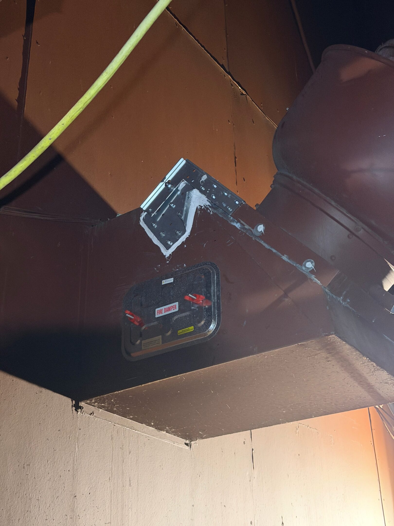 A black ceiling smoke detector with a red indicator light.