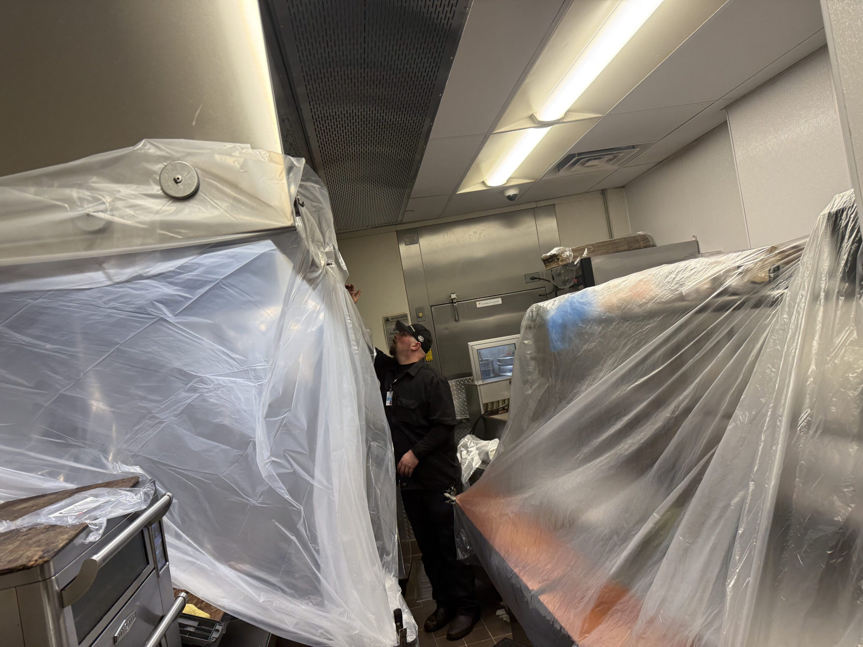 People working in a room with furniture covered in plastic sheets.