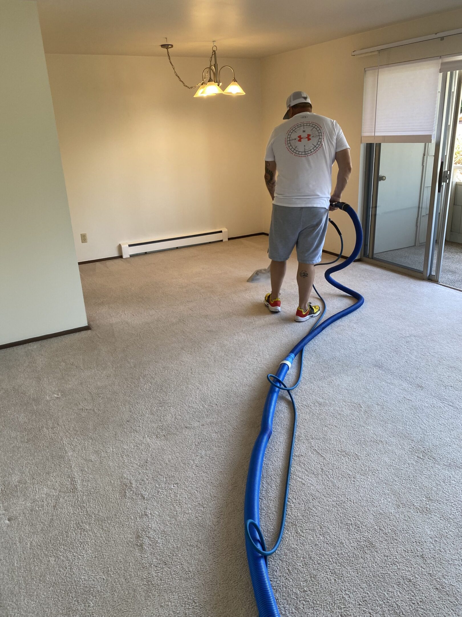 Person cleaning carpet using professional equipment in an empty room.