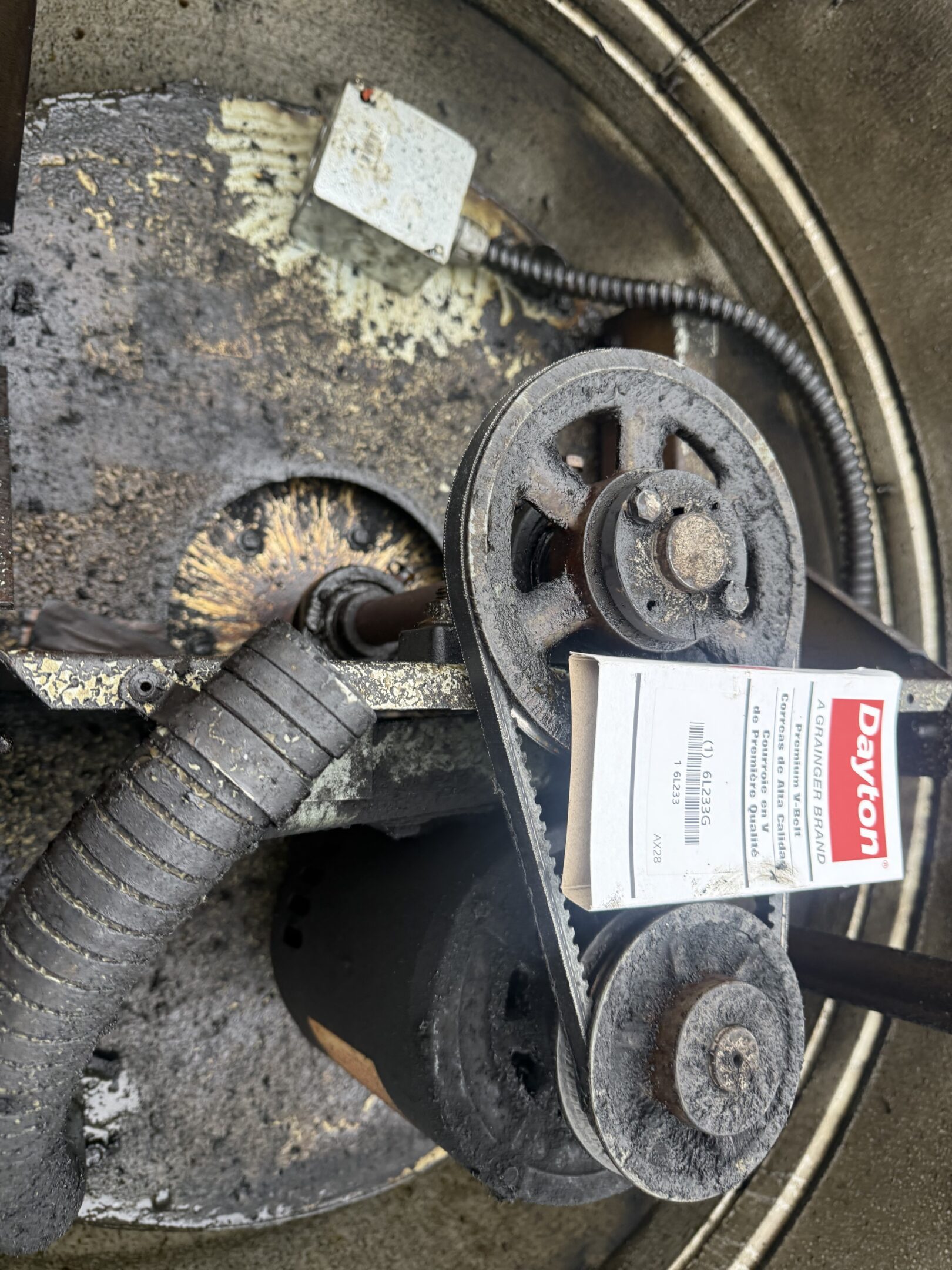 Close-up of a car engine belt system with a label attached.