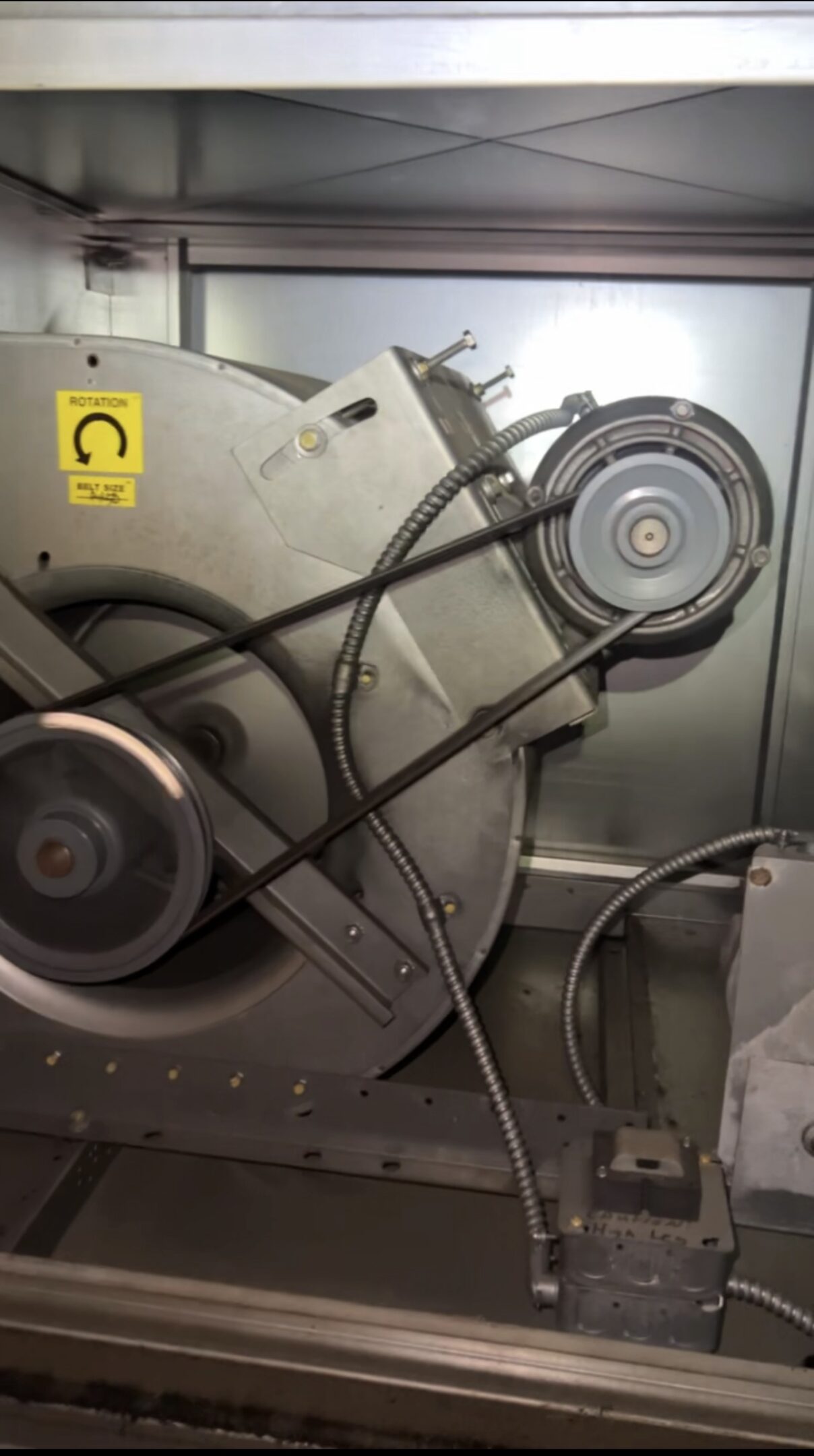Close-up of a mechanical pulley system with belts inside a machine.